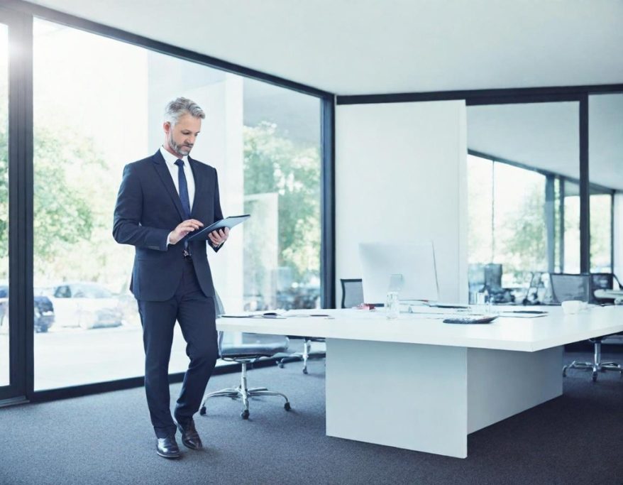 Businessman in a suit using a tablet in a modern office setting.